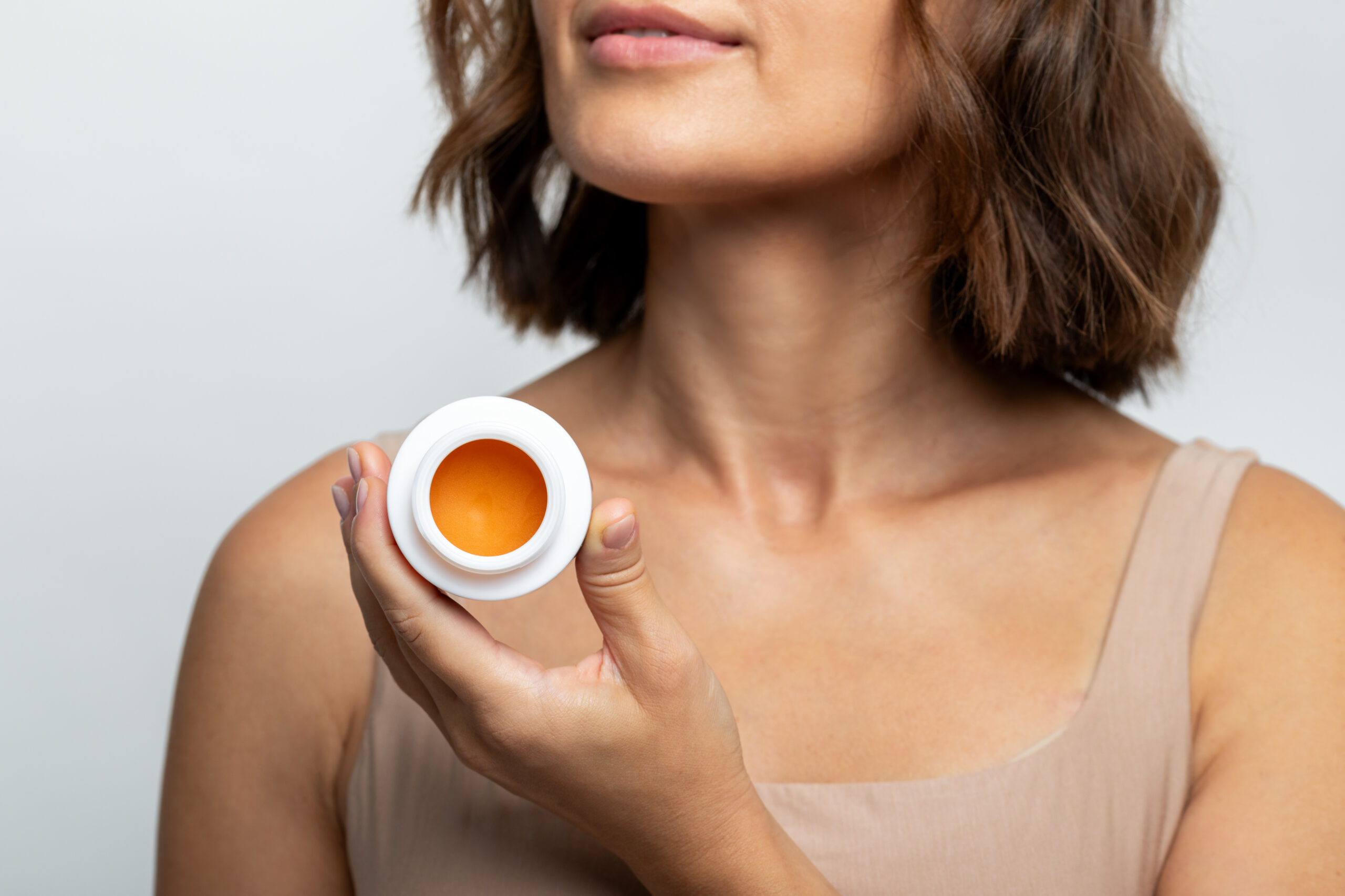 Fotografia reklamowa, social media marki kosmetycznej. Modelka trzyma krem w ręce.